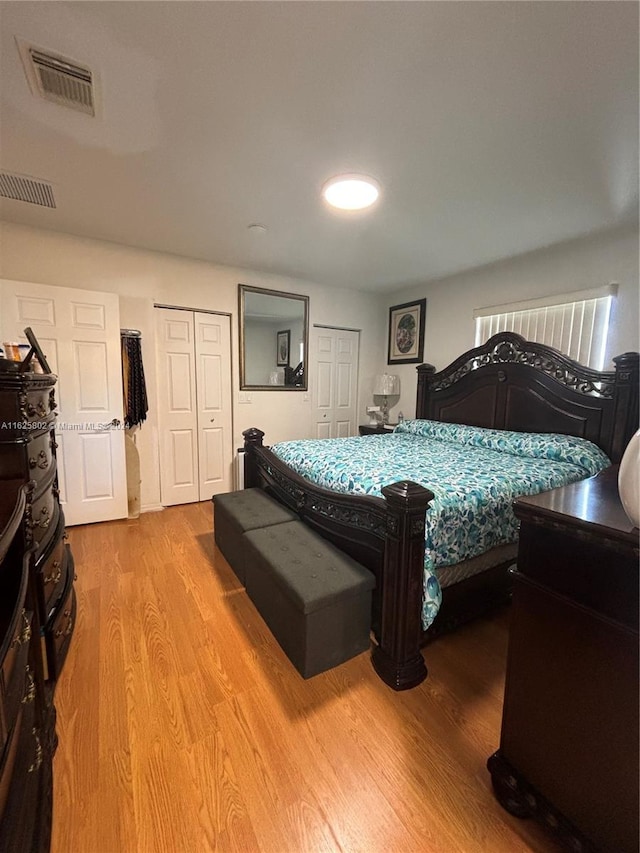 bedroom featuring hardwood / wood-style flooring and two closets