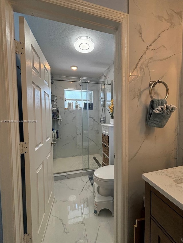 bathroom with vanity, toilet, an enclosed shower, and a textured ceiling