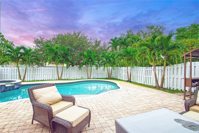 pool at dusk with an in ground hot tub, central air condition unit, and a patio