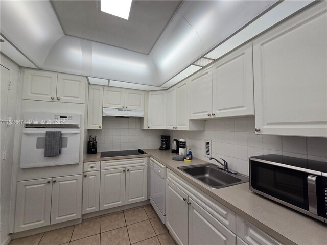 kitchen with tasteful backsplash, white appliances, white cabinets, sink, and light tile patterned flooring