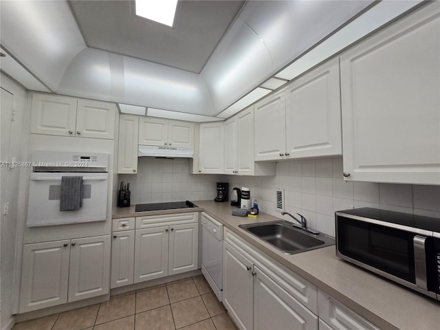 kitchen with white appliances, light countertops, under cabinet range hood, white cabinetry, and a sink