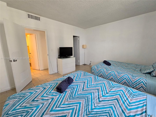 bedroom with visible vents, a textured ceiling, and light tile patterned floors