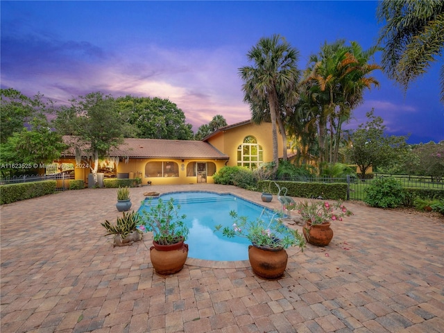 pool at dusk featuring a patio