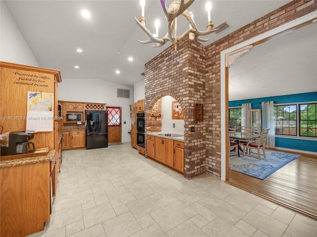 kitchen featuring brick wall, light wood-type flooring, black appliances, and a notable chandelier