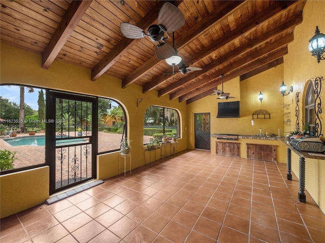 unfurnished sunroom featuring ceiling fan, lofted ceiling with beams, sink, and wooden ceiling