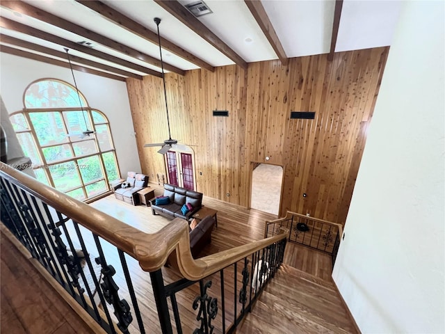 stairs with hardwood / wood-style floors, beamed ceiling, and wood walls