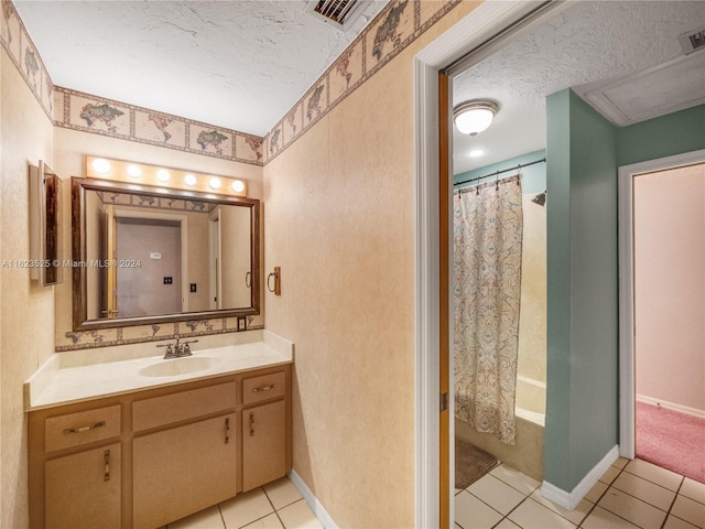 bathroom with tile patterned floors, shower / bath combo with shower curtain, vanity, and a textured ceiling