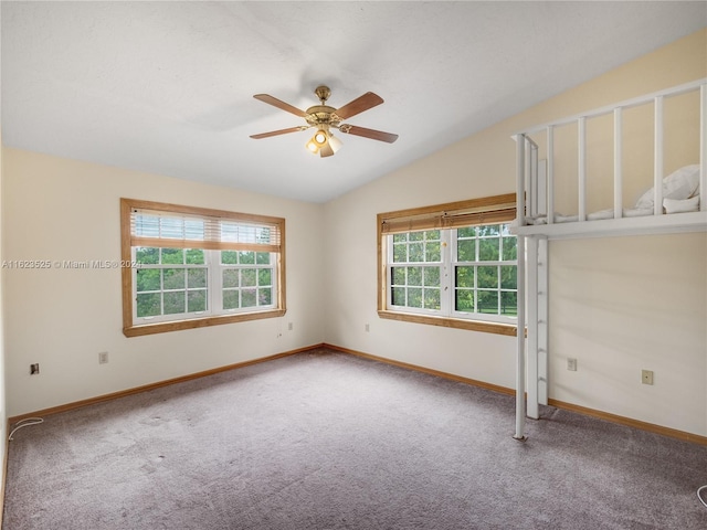 carpeted empty room with lofted ceiling, a wealth of natural light, and ceiling fan