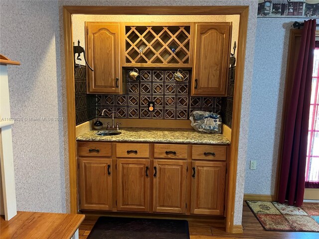 kitchen featuring wood-type flooring, light stone counters, and sink