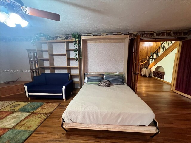 bedroom with dark hardwood / wood-style floors, ceiling fan, and a textured ceiling