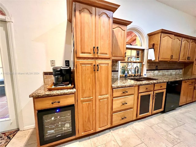 kitchen with tasteful backsplash, dark stone countertops, black dishwasher, and sink