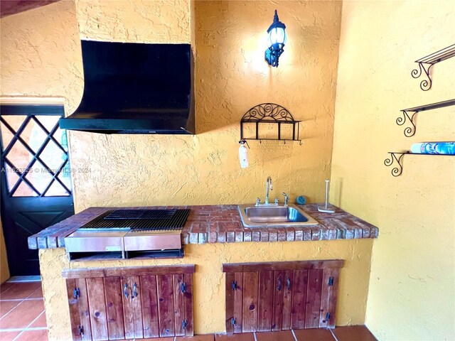 kitchen with light tile patterned flooring, premium range hood, gas stovetop, and sink