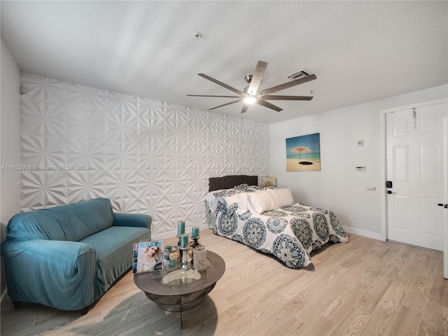 bedroom featuring light hardwood / wood-style flooring, a textured ceiling, and ceiling fan