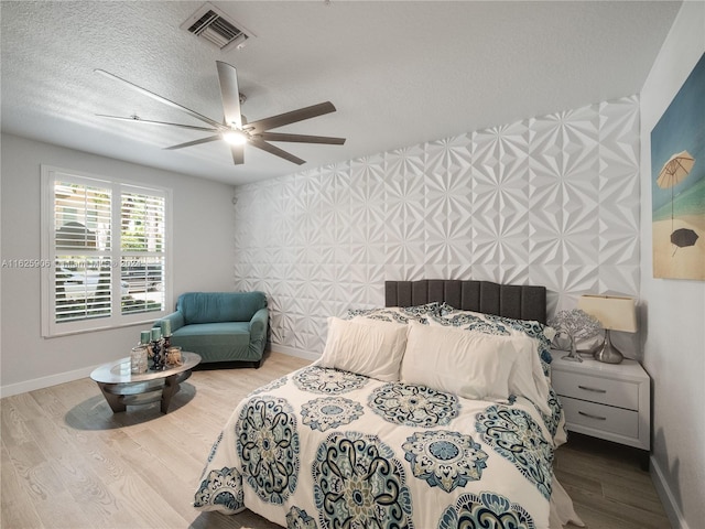 bedroom with a textured ceiling, ceiling fan, and hardwood / wood-style floors