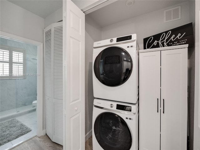 clothes washing area featuring light wood-type flooring and stacked washing maching and dryer