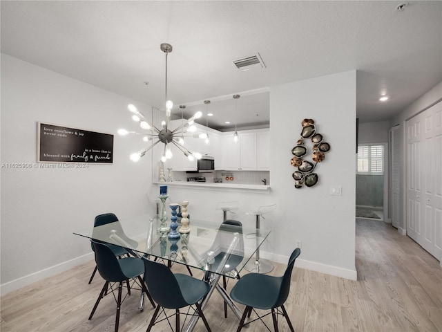 dining space with light hardwood / wood-style flooring and a chandelier