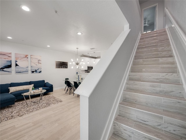 staircase featuring light hardwood / wood-style floors and a chandelier