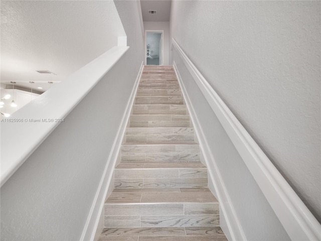 stairs with wood-type flooring and a textured ceiling