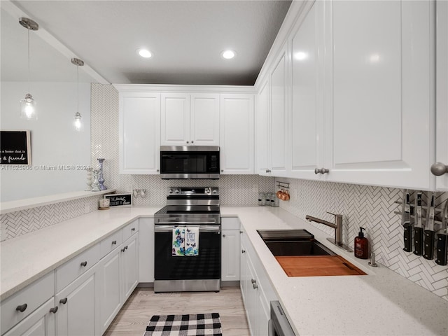 kitchen featuring light hardwood / wood-style floors, appliances with stainless steel finishes, white cabinets, and tasteful backsplash