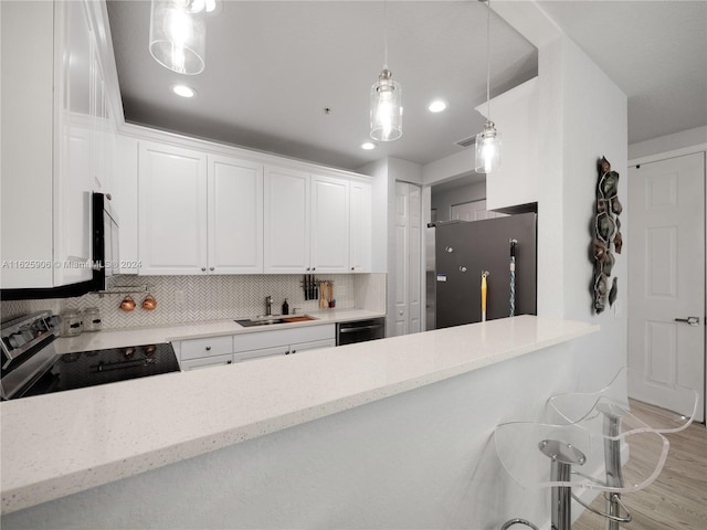 kitchen with white cabinets, fridge, electric stove, hanging light fixtures, and decorative backsplash