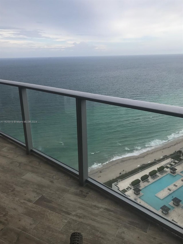 balcony featuring a view of the beach and a water view