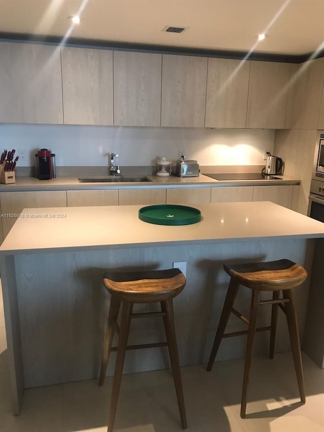 kitchen with a kitchen breakfast bar, a kitchen island, stainless steel microwave, and sink