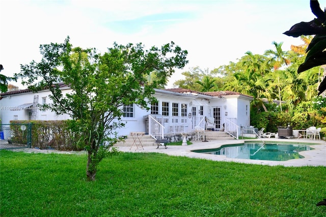 back of house featuring a patio, a lawn, and a fenced in pool