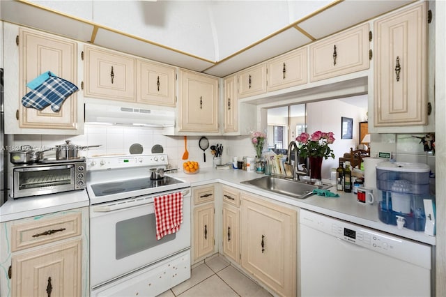 kitchen with light tile patterned flooring, premium range hood, decorative backsplash, white appliances, and sink