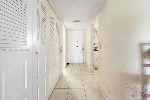 corridor with a textured ceiling and light tile patterned floors