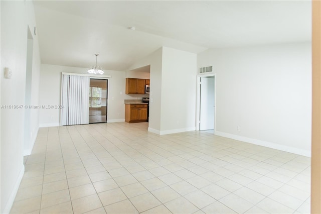 tiled spare room with lofted ceiling and a notable chandelier