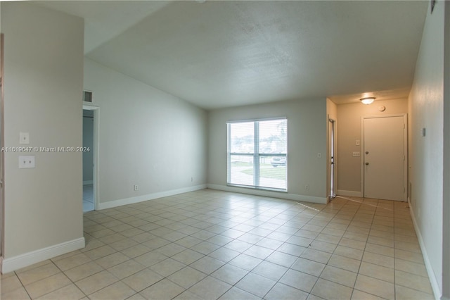 spare room featuring light tile patterned floors and lofted ceiling