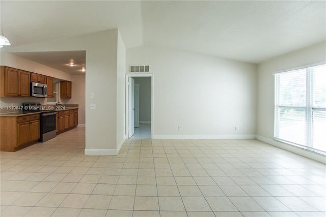 kitchen with light tile patterned floors, vaulted ceiling, and appliances with stainless steel finishes