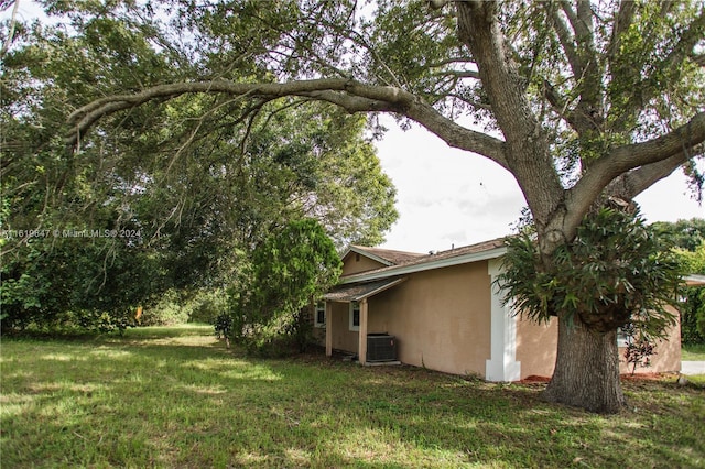 view of side of property featuring cooling unit and a yard