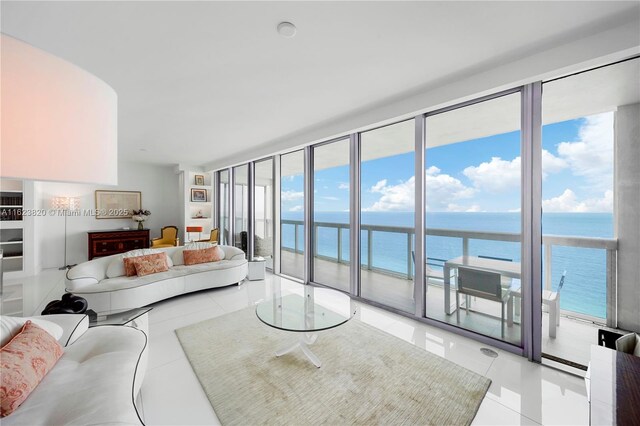 tiled living room with a wall of windows, a water view, a beach view, and plenty of natural light