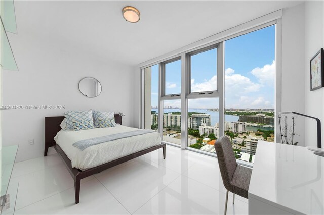 tiled bedroom with a wall of windows, a water view, and multiple windows