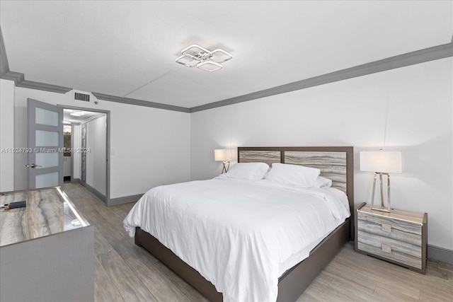 bedroom featuring crown molding and light hardwood / wood-style floors