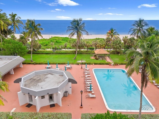 view of pool featuring a water view, a lawn, a beach view, and a patio area