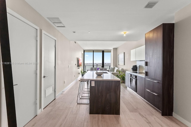 480 NE 31st St Unit 1005, Miami, FL 33137 - kitchen featuring modern cabinets, a breakfast bar, light countertops, a center island, and light wood-type flooring