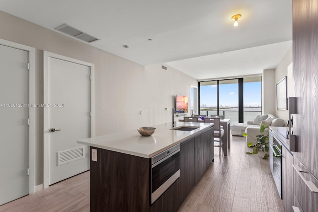 480 NE 31st St Unit 1005, Miami, FL 33137 - kitchen featuring modern cabinets, stainless steel microwave, dark brown cabinetry, floor to ceiling windows, and light wood-type flooring