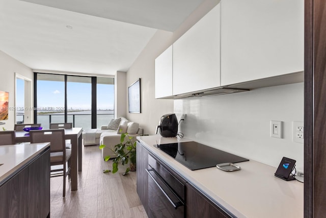 480 NE 31st St Unit 1005, Miami, FL 33137 - kitchen with black electric cooktop, wall oven, light countertops, white cabinets, and a wall of windows