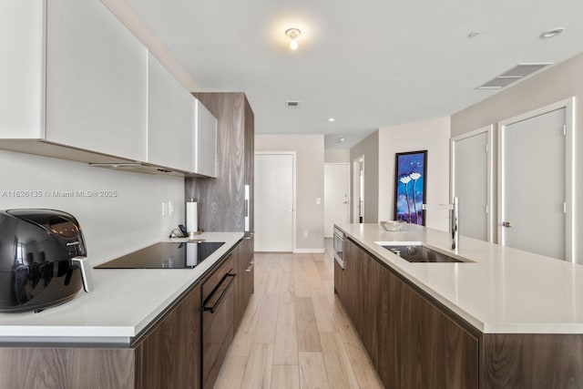 480 NE 31st St Unit 1005, Miami, FL 33137 - kitchen featuring modern cabinets, black electric stovetop, a spacious island, white cabinets, and light wood finished floors