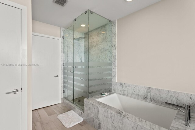 480 NE 31st St Unit 1005, Miami, FL 33137 - full bathroom featuring a garden tub, a stall shower, wood finished floors, and recessed lighting