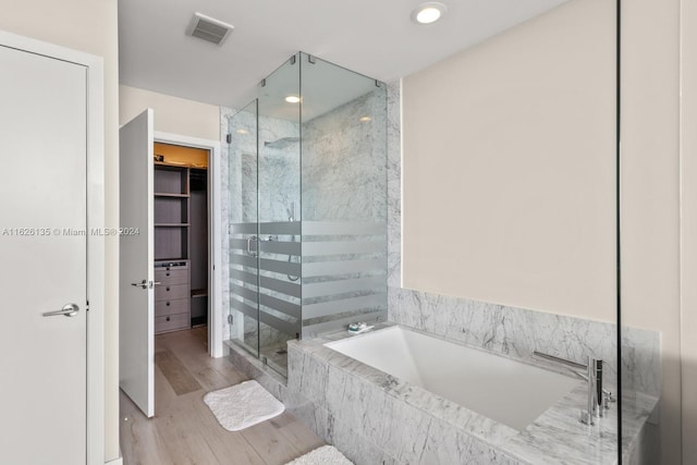 bathroom with independent shower and bath and hardwood / wood-style floors