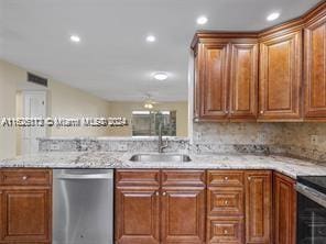 kitchen featuring light stone counters, dishwasher, sink, and decorative backsplash