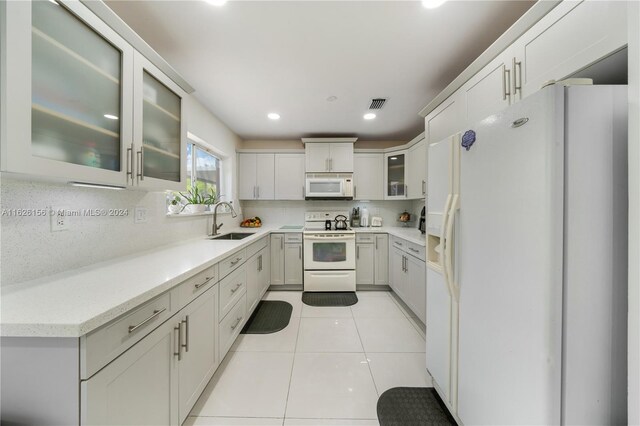 kitchen featuring tasteful backsplash, white cabinets, white appliances, sink, and light tile patterned floors