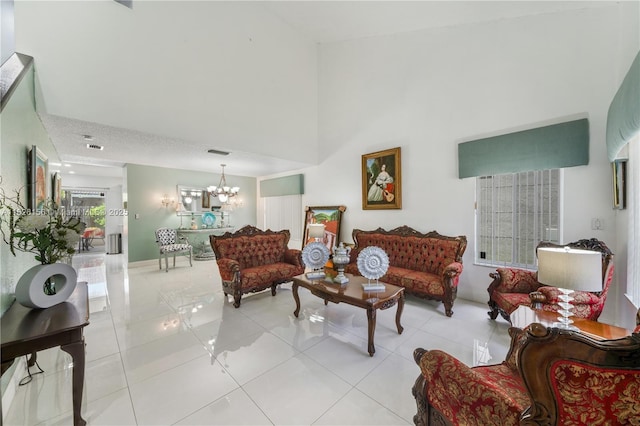 living area featuring an inviting chandelier, visible vents, light tile patterned flooring, and a towering ceiling