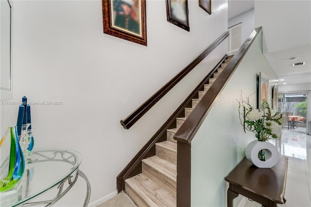 staircase with visible vents, baseboards, and tile patterned floors