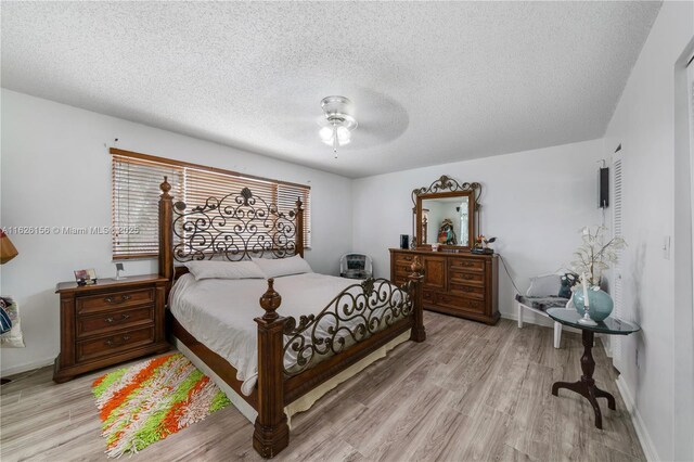 bedroom featuring light wood-style floors, a textured ceiling, ceiling fan, and baseboards