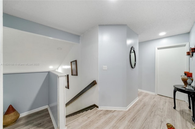 hallway with recessed lighting, baseboards, an upstairs landing, and wood finished floors