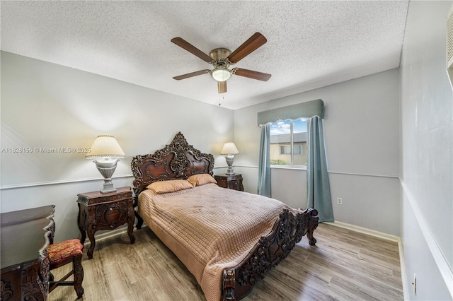 bedroom featuring baseboards, a ceiling fan, a textured ceiling, and wood finished floors